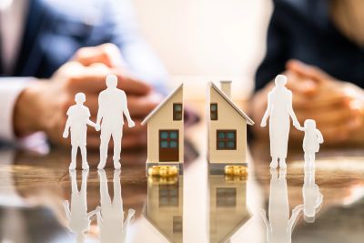Paper cutout figures of two families and miniature houses on a table.