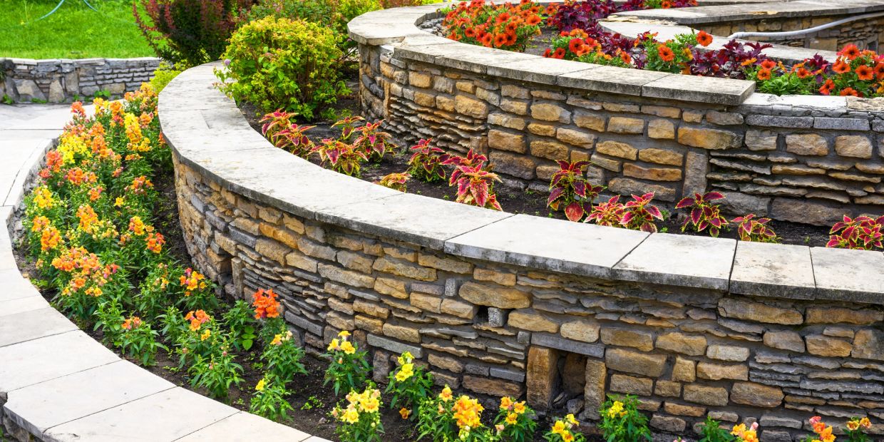 Curved stone garden beds with colorful flowers.