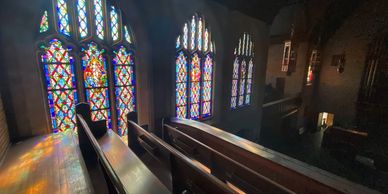 Sunlight streams through colorful stained glass windows in a church.
