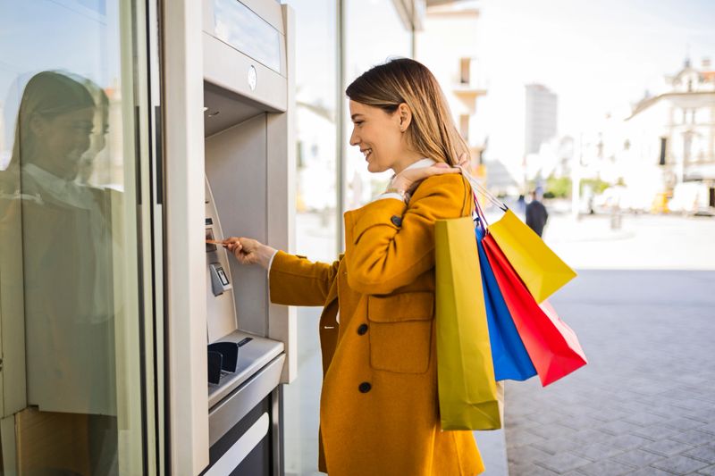 Young woman taking the money for shopping from the ATM