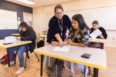 Teacher assists student in classroom.