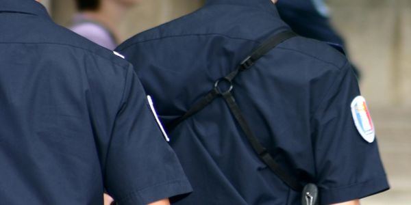 Two police officers in uniform standing with their backs to the camera.