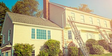 A two-story house with ladders set up for roof work.