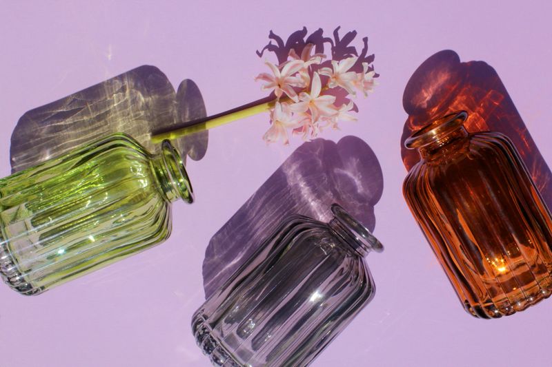 Glassware vases reflect sunlight shadow effect on a purple background. Play of shadows and sunlight. Summer still life concept.