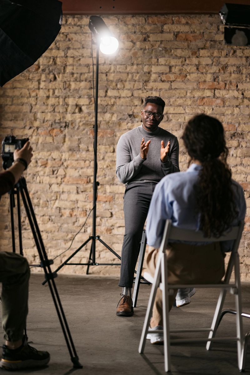Handsome man sitting on a bar stool and giving an interview to a female journalist in front of him, gesturing with his hands while he's talking