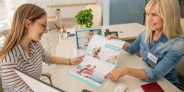 A travel agent shows vacation options to a smiling client.
