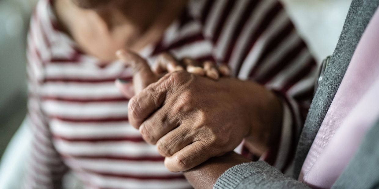 Two people holding hands in a comforting gesture.