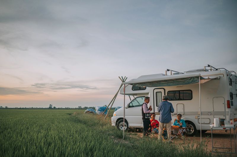 Asian Chinese senior friends enjoy dinner beside campervan parked at paddy field