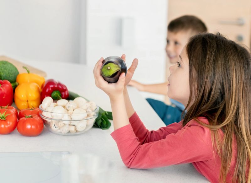 Sister and brother listening to their parents as they explain why should they use more vegetables in their meals, as it is more ethical.
