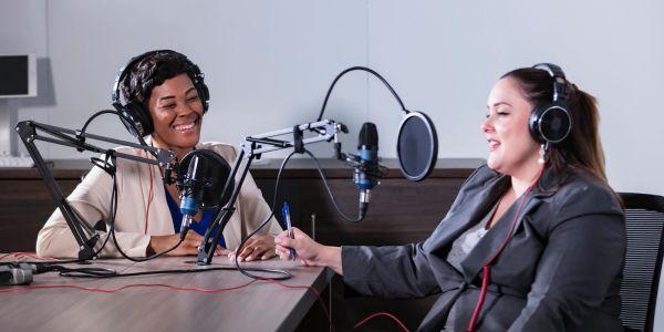 Two women recording a podcast conversation in a studio.