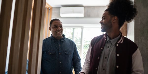 Two men smiling and interacting indoors.