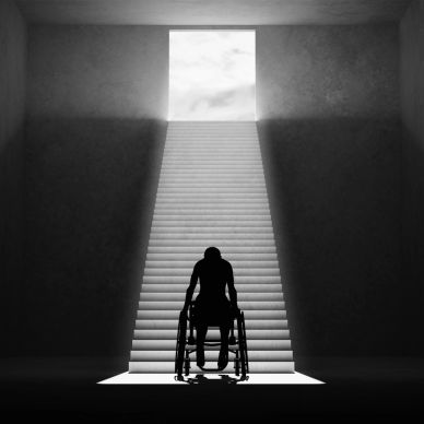 Person in wheelchair facing long staircase and light.
