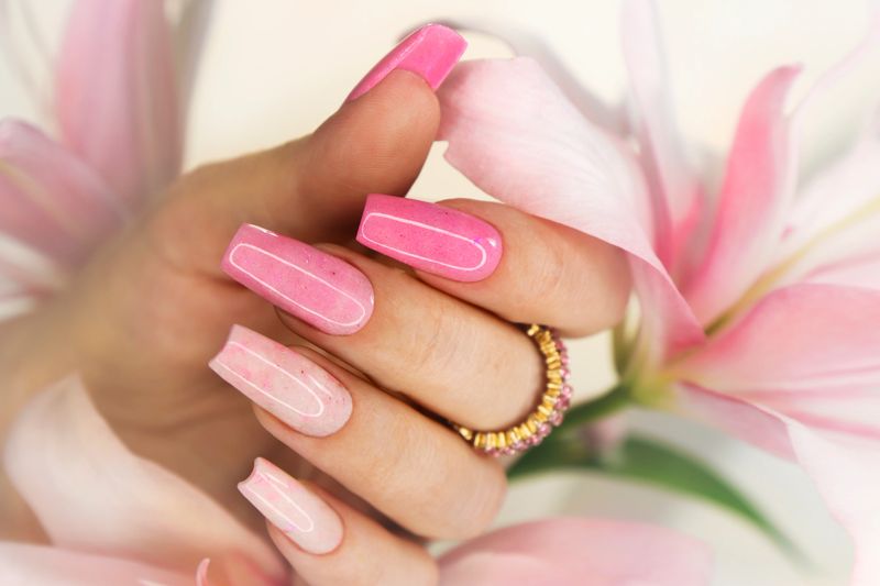 Pink elongated nail extension with fine glitter.