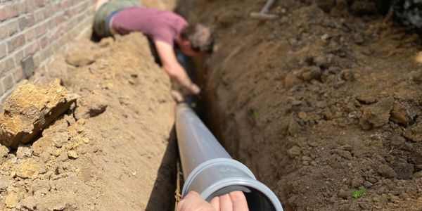 A man is digging in the ground with a pipe.