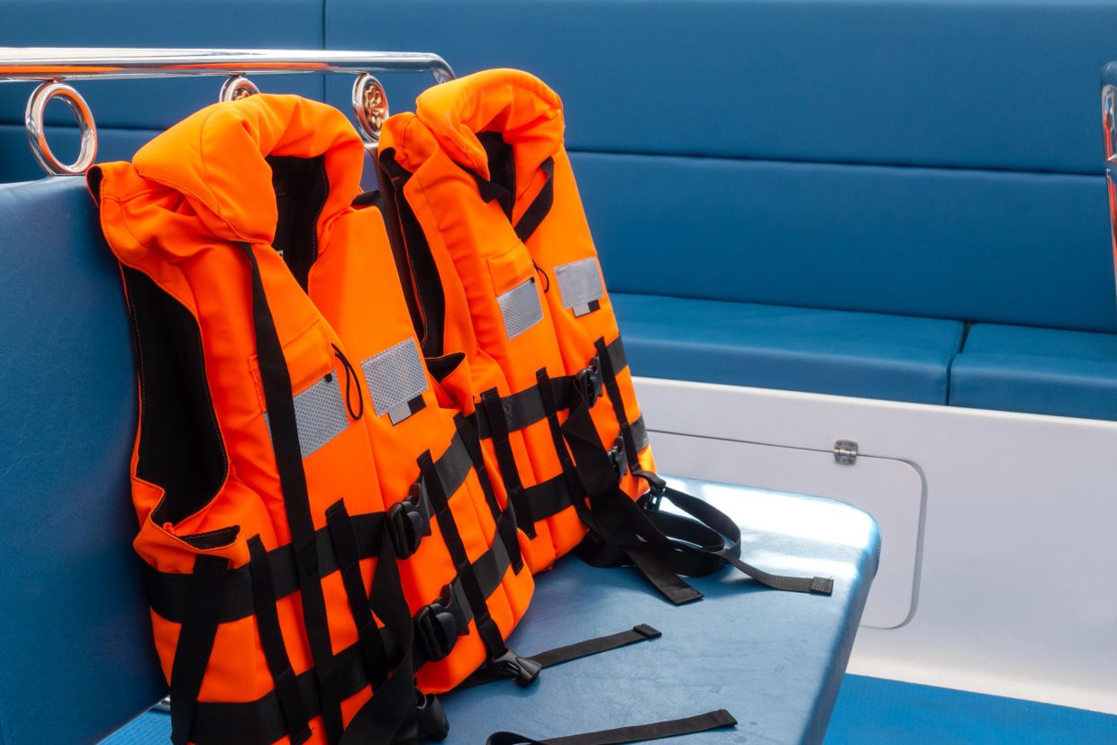 Two orange life jackets on a boat bench.