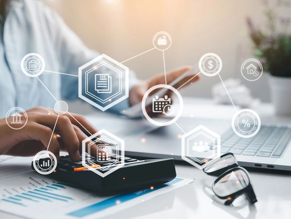 Person using a calculator and smartphone with financial icons overlay.