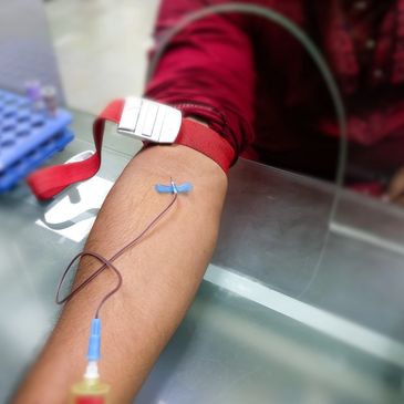 Close-up of a blood draw procedure with a tourniquet and needle.