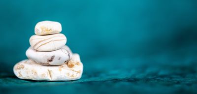 Stack of smooth white stones against a teal background.