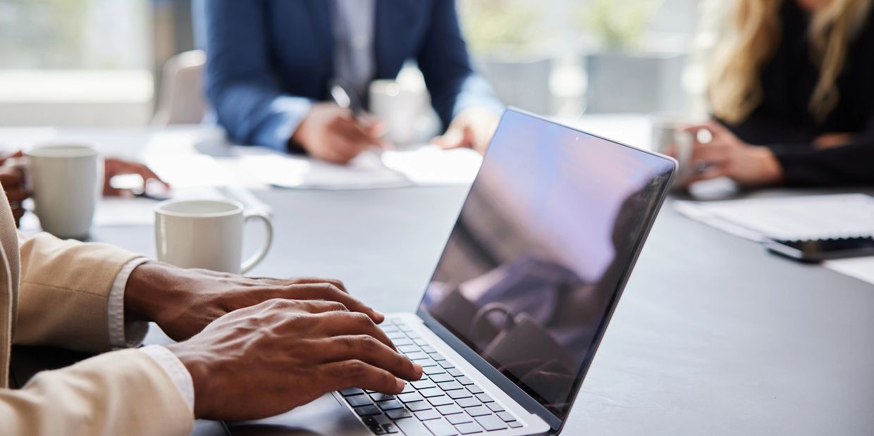 Person typing on a laptop in a meeting.