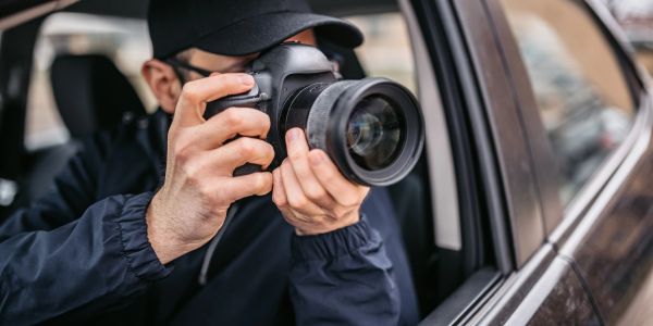 Person taking a photo through a car window with a professional camera.