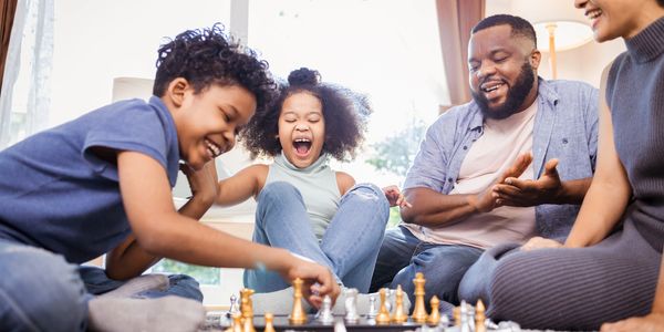 Family enjoying a lively chess game together in a cozy room.
