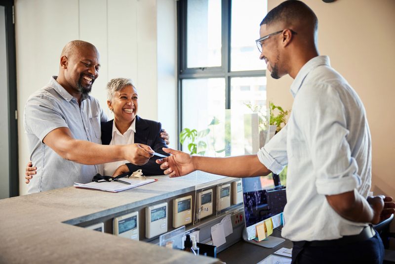 Smiling mature couple giving a cardkey to a concierge at the reception desk of a hotel during checkout