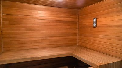 Cozy wooden sauna interior with bench seating and temperature gauges.