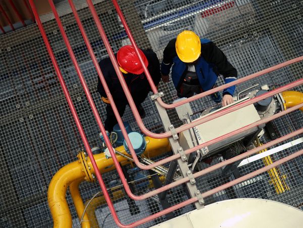 Workers inspecting industrial metal piping
