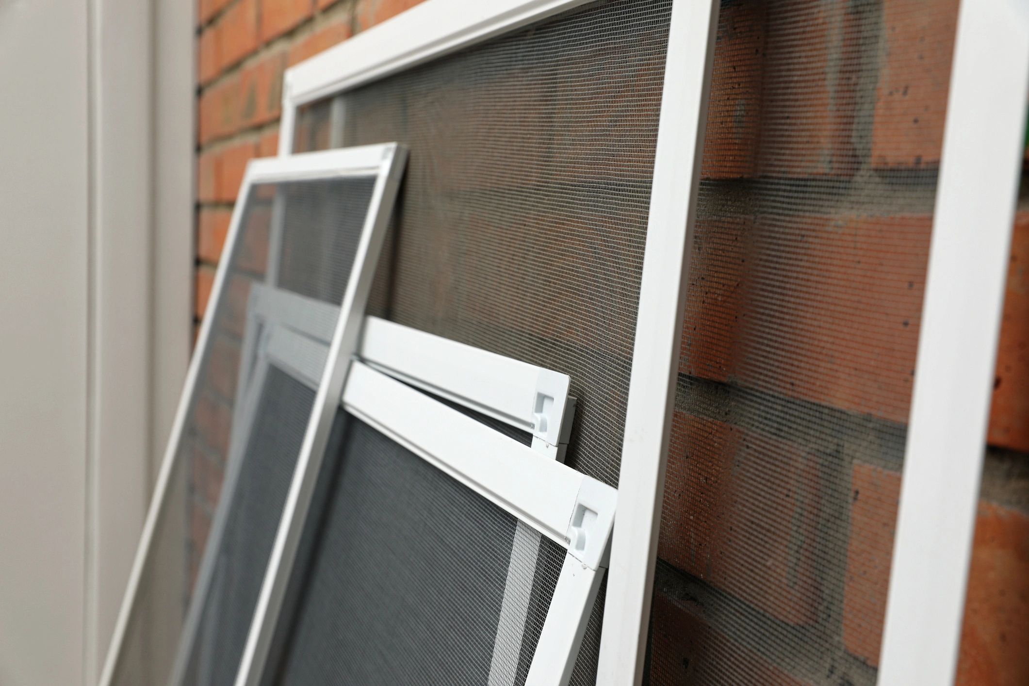 Window screens leaning against a brick wall.