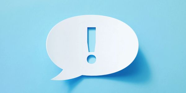 Speech bubble with exclamation mark on blue background.