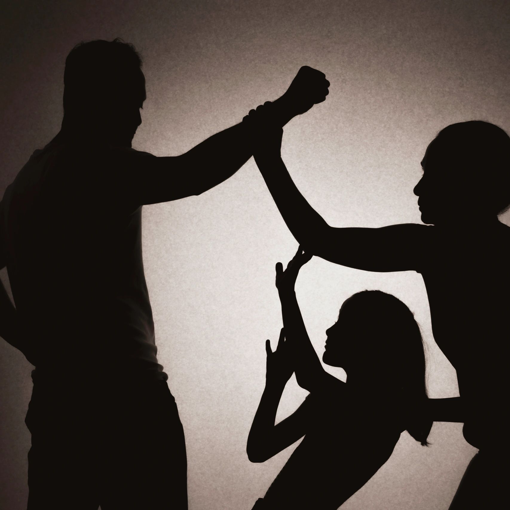 Silhouettes showing a man raising his fist, with a woman and child raising hands to protect themselves.