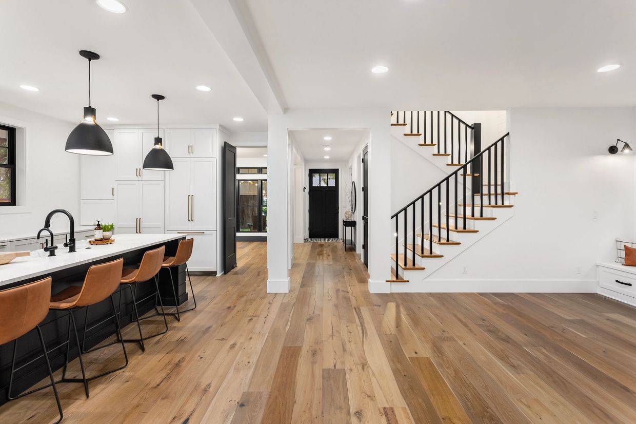 Modern kitchen and hallway with wooden floors and black accents.