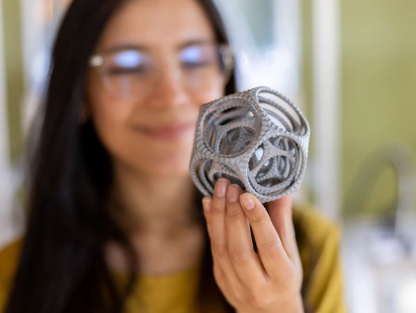 Woman holding a detailed 3D-printed geometric object.