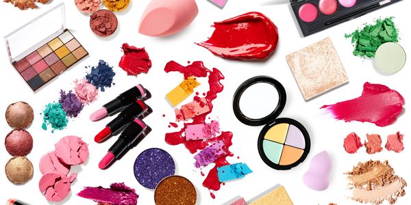 Colorful makeup products and swatches scattered on white background.