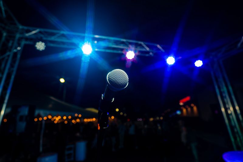 Comedy or Live Music Show at Night Outdoors with Microphone and Blue Lights Nightlife.