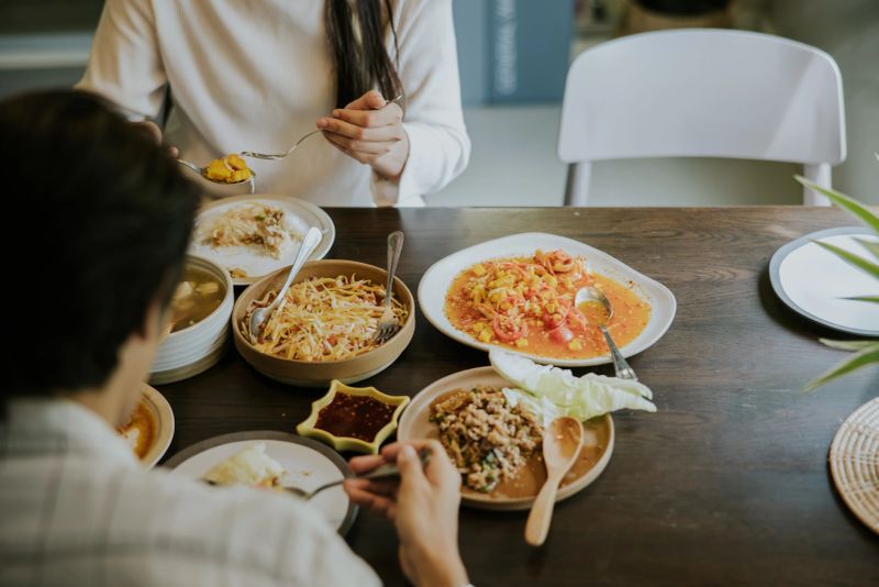 Young asian couple enjoy their Sunday lunch with delivery Somtum, Laab, and spicy with Thai Isan food together.