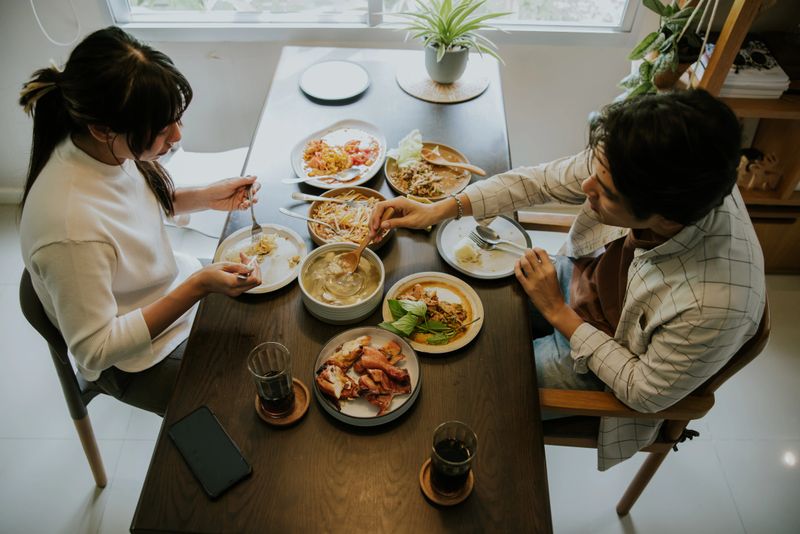 Asian couple enjoy their lunch meal together, ordering delivery food for sharing and eating together.