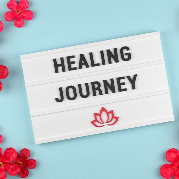 A sign reads 'Healing Journey' surrounded by red flowers on a blue background.