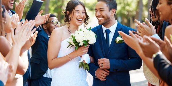 Newlywed couple smiling happily as guests cheer and applaud.
