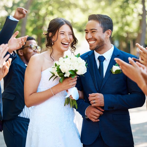 Happy bride and groom smiling amid congratulating guests.