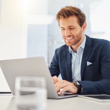 Smiling businessman working on laptop in bright office.