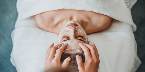 Person receiving a facial treatment with cream applied on the face.