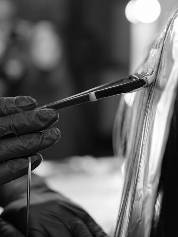 Close-up of an artist painting with a brush while wearing gloves.