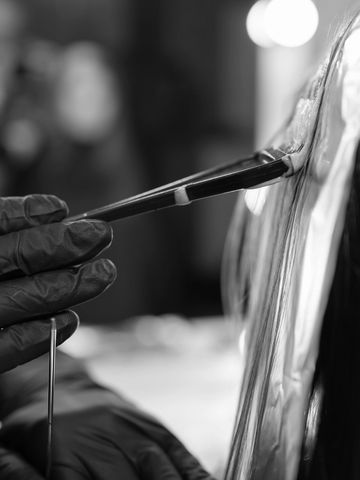 Close-up of an artist painting with a brush while wearing gloves.