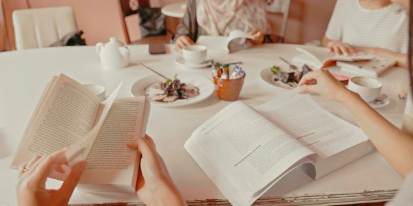 People reading books over coffee at a table.