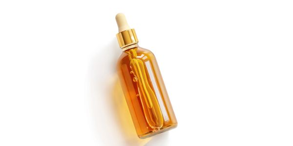 Amber glass dropper bottle with golden cap on white background.