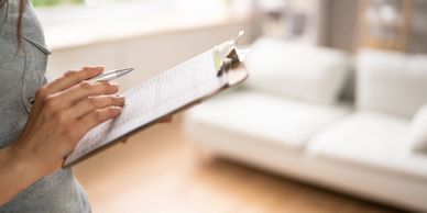 Person holding a pen and clipboard with a checklist in a bright room.