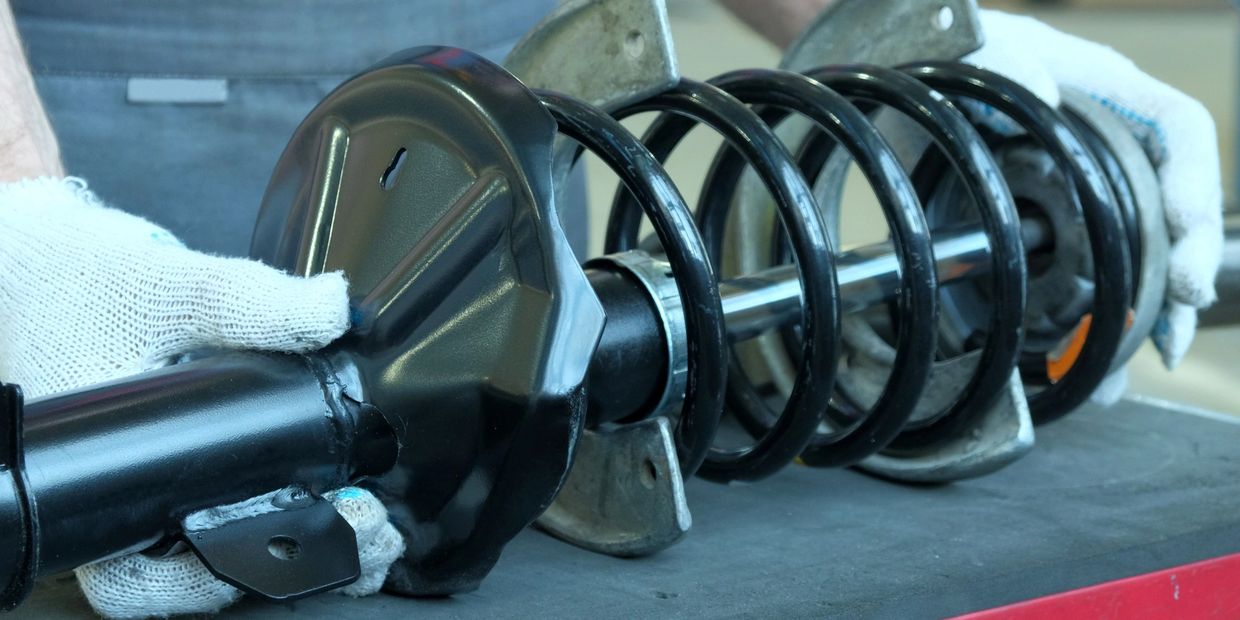 hands holding springs for automotive suspension strut