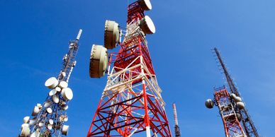 Tall red and white telecommunications towers against a clear blue sky.