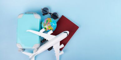 Travel essentials including suitcase, globe, airplane model, passport, and sunglasses on blue background.